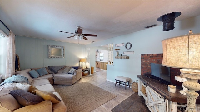 living room featuring a textured ceiling, light hardwood / wood-style floors, ceiling fan, and a healthy amount of sunlight