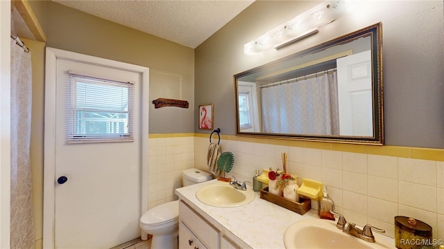 bathroom with tile walls, vanity, a textured ceiling, and toilet