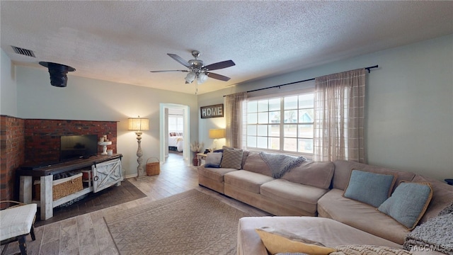 living room featuring ceiling fan, hardwood / wood-style floors, and a textured ceiling