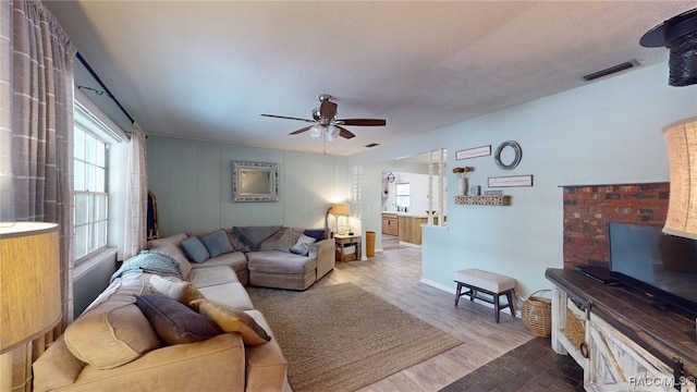 living room with hardwood / wood-style floors, a textured ceiling, and ceiling fan