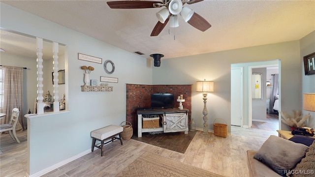 living room featuring ceiling fan, light hardwood / wood-style flooring, and a textured ceiling