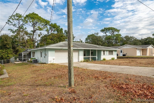 view of front facade featuring a front yard, central AC unit, and a garage