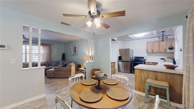 dining room with ceiling fan, sink, light hardwood / wood-style floors, and a textured ceiling