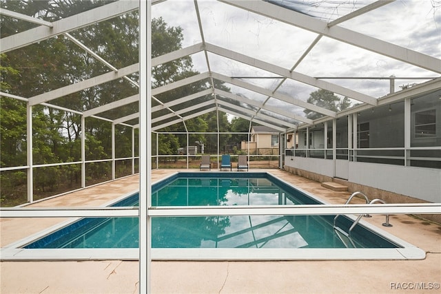 view of swimming pool with a patio area and a lanai