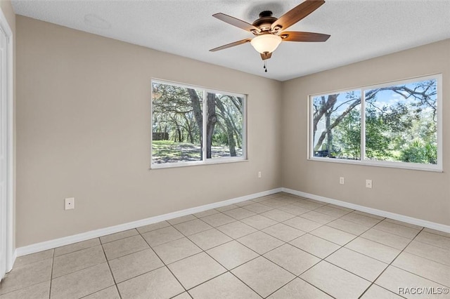 tiled spare room featuring ceiling fan, a textured ceiling, and a wealth of natural light