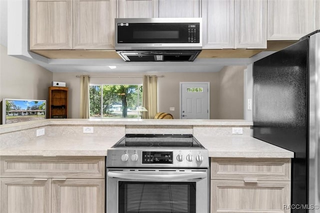 kitchen featuring stainless steel electric stove, refrigerator, and light brown cabinetry