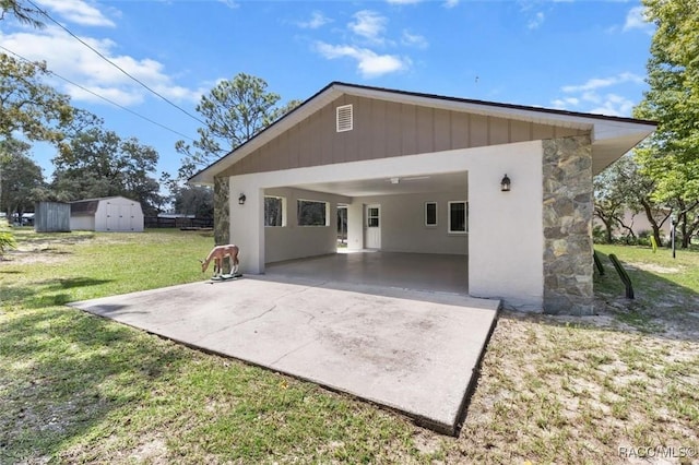 rear view of house featuring a lawn, a carport, and a storage unit