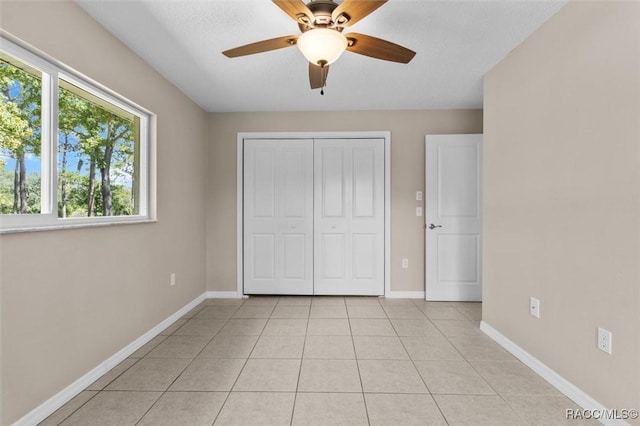 unfurnished bedroom with light tile patterned flooring, ceiling fan, a closet, and a textured ceiling