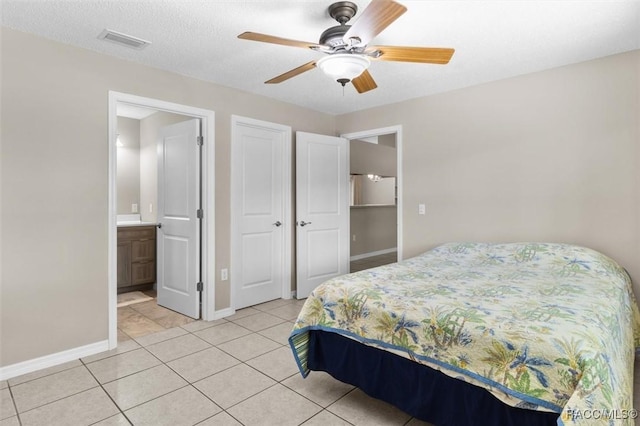 tiled bedroom with ceiling fan, connected bathroom, and a textured ceiling