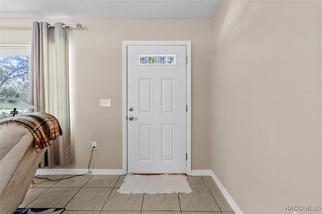 entryway with light tile patterned floors and a textured ceiling