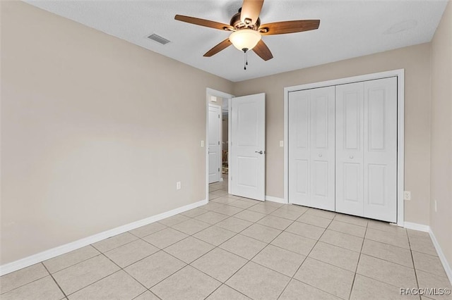 unfurnished bedroom with light tile patterned flooring, ceiling fan, and a closet