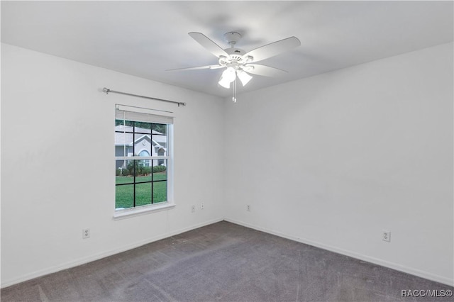 spare room featuring dark colored carpet and ceiling fan