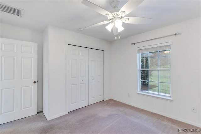 unfurnished bedroom featuring ceiling fan, light carpet, and a closet