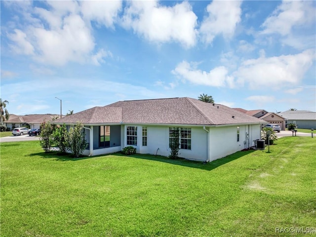 rear view of house with a sunroom, a yard, and central AC