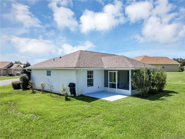 rear view of house featuring a lawn, a sunroom, and a patio