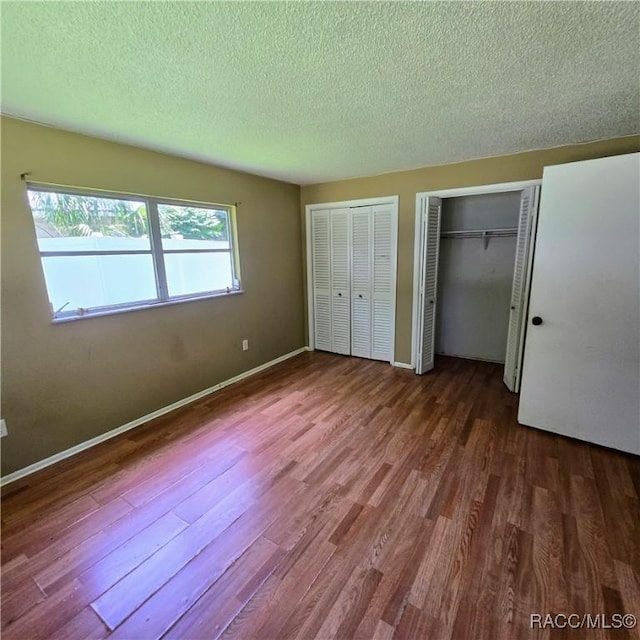 9227 N Fawn Way, Citrus Springs, FL 34434 - unfurnished bedroom with wood finished floors, two closets, and a textured ceiling