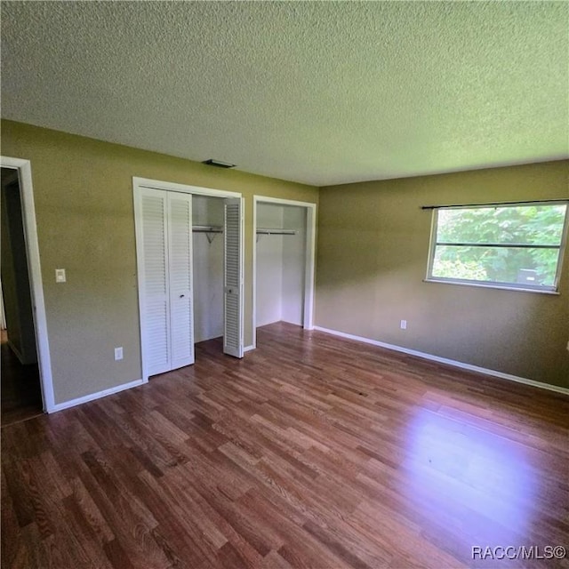 9227 N Fawn Way, Citrus Springs, FL 34434 - unfurnished bedroom featuring a textured ceiling, dark wood-style flooring, and two closets