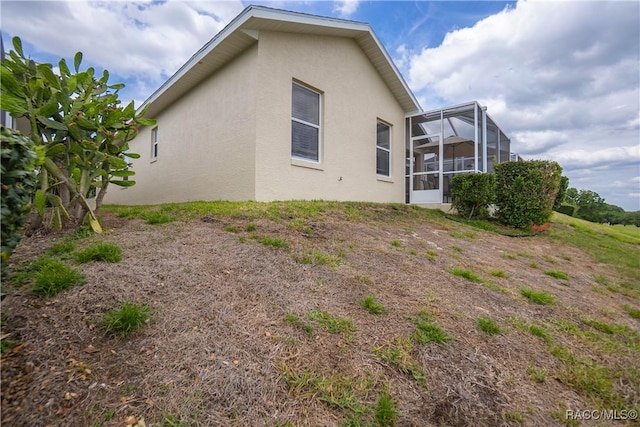 rear view of house with stucco siding and a lanai