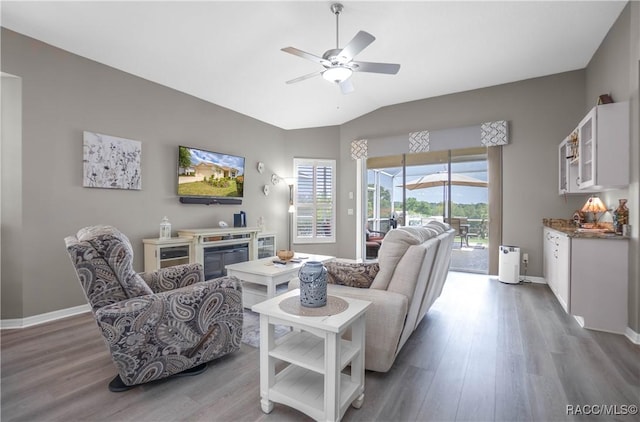 living room featuring wood finished floors, ceiling fan, vaulted ceiling, and baseboards