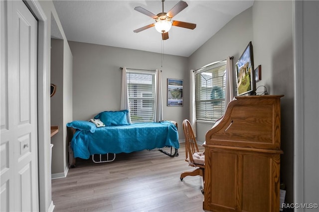bedroom with lofted ceiling, light wood-type flooring, a ceiling fan, and baseboards