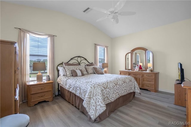 bedroom with visible vents, ceiling fan, baseboards, light wood finished floors, and vaulted ceiling