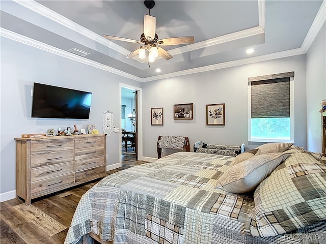 bedroom featuring ceiling fan, crown molding, dark wood-type flooring, and a tray ceiling