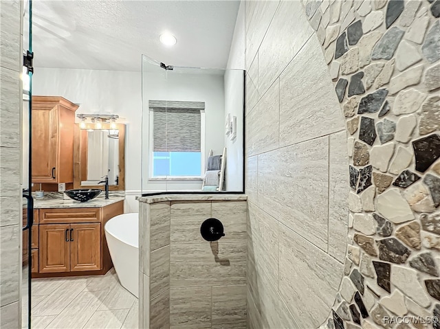 bathroom featuring plus walk in shower, vanity, and a textured ceiling