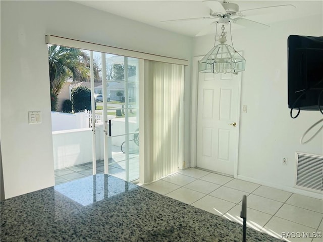 unfurnished dining area with ceiling fan with notable chandelier and light tile patterned floors