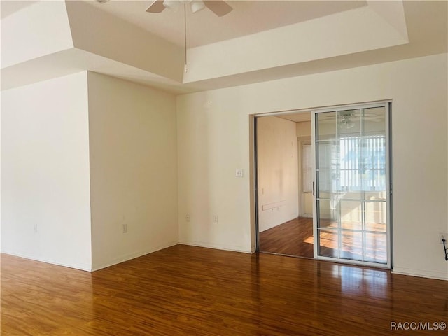 unfurnished room featuring ceiling fan, wood-type flooring, and a tray ceiling