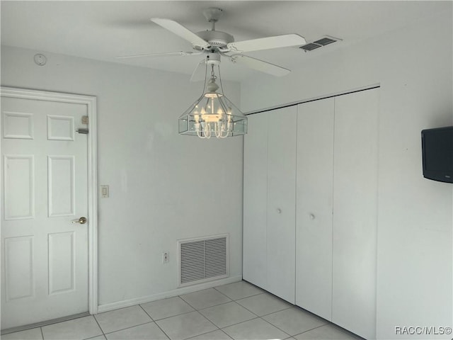 tiled spare room with ceiling fan with notable chandelier