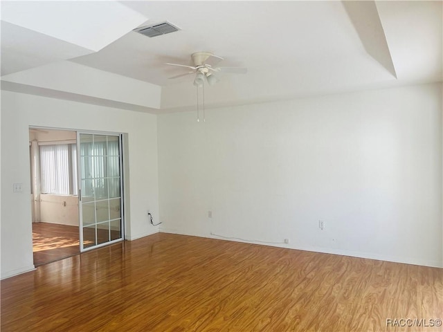 spare room with ceiling fan, a raised ceiling, and hardwood / wood-style flooring