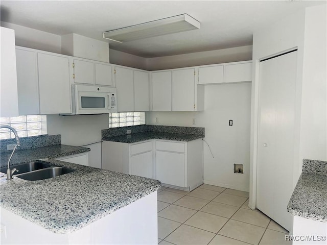 kitchen featuring sink, white cabinetry, stone countertops, and light tile patterned floors