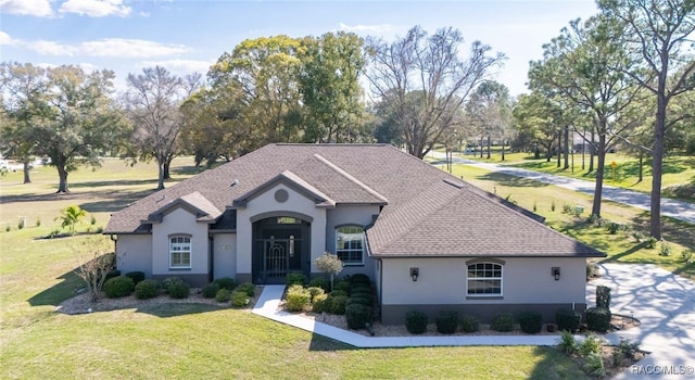 view of front of house featuring a shingled roof, a front lawn, and stucco siding