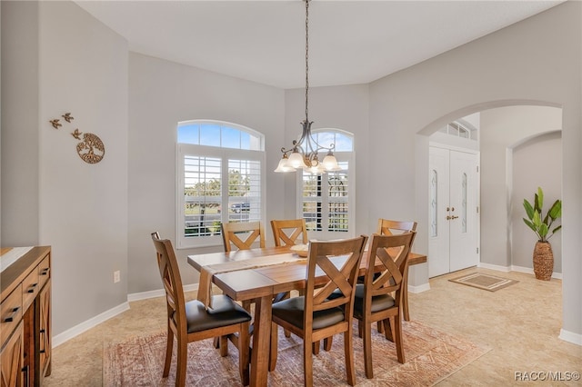 dining area featuring arched walkways, a chandelier, and baseboards