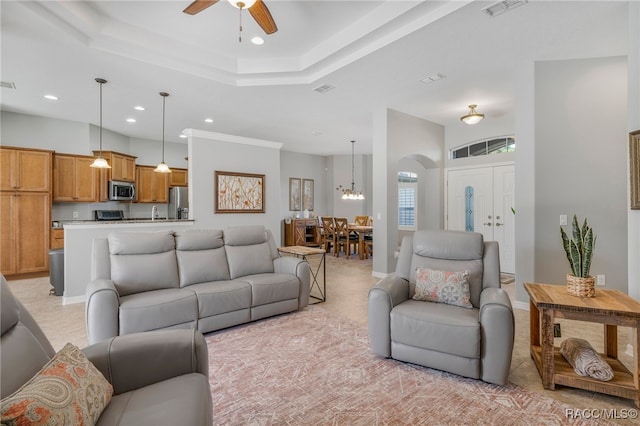 living room featuring arched walkways, recessed lighting, visible vents, a ceiling fan, and a tray ceiling