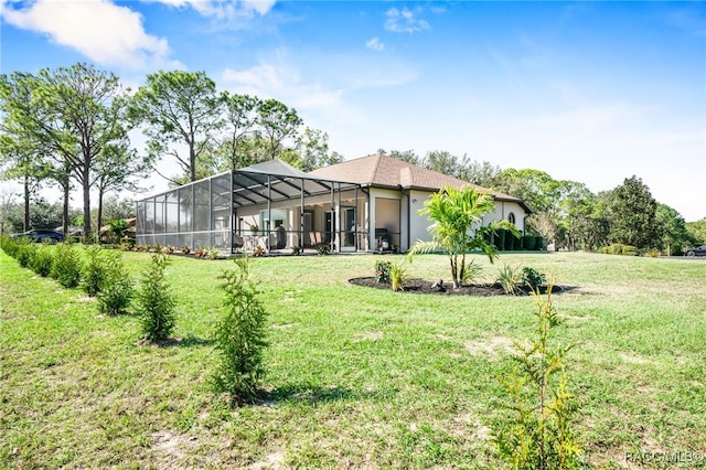 rear view of property with an attached garage, a lanai, and a yard