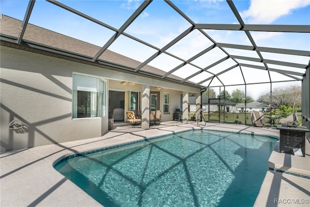 pool with a lanai, a patio area, and ceiling fan