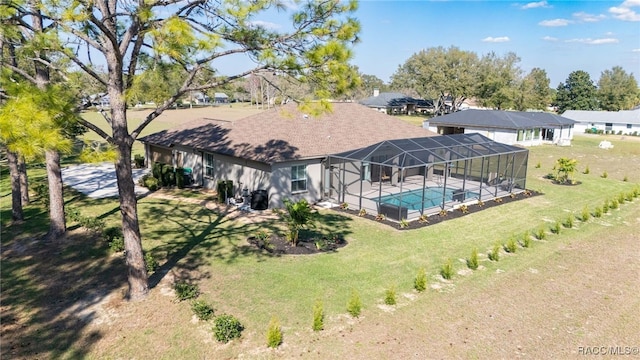 back of property featuring an outdoor pool, glass enclosure, and a lawn