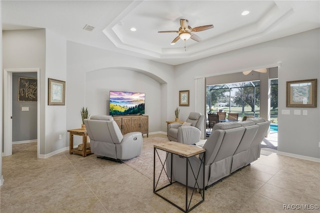 living room with a sunroom, baseboards, and a tray ceiling