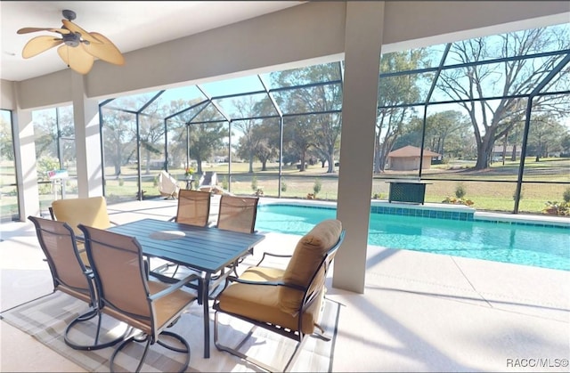 outdoor pool with glass enclosure, ceiling fan, and a patio area