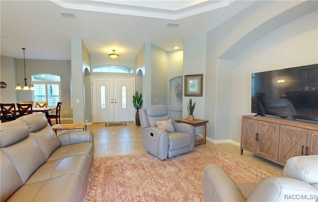 living area with light tile patterned floors, a raised ceiling, visible vents, and baseboards