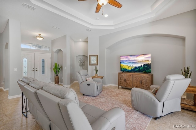 living area featuring light tile patterned floors, baseboards, visible vents, and arched walkways