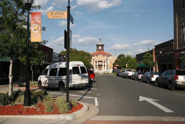 view of road featuring street lights, curbs, and traffic signs