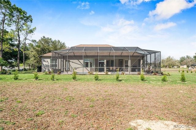 back of property with glass enclosure and a lawn