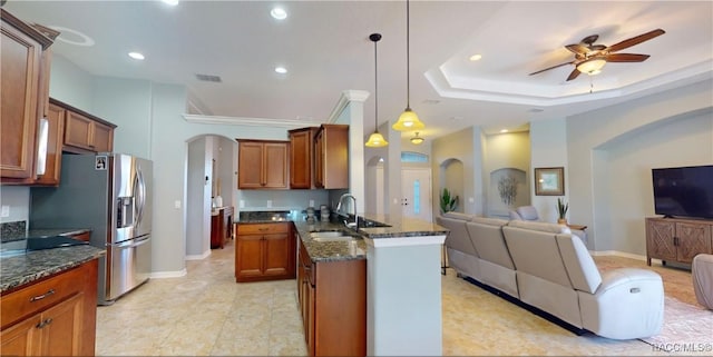 kitchen featuring arched walkways, brown cabinetry, open floor plan, a sink, and a peninsula