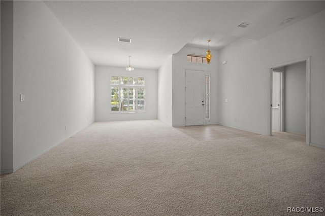empty room with light colored carpet and a chandelier