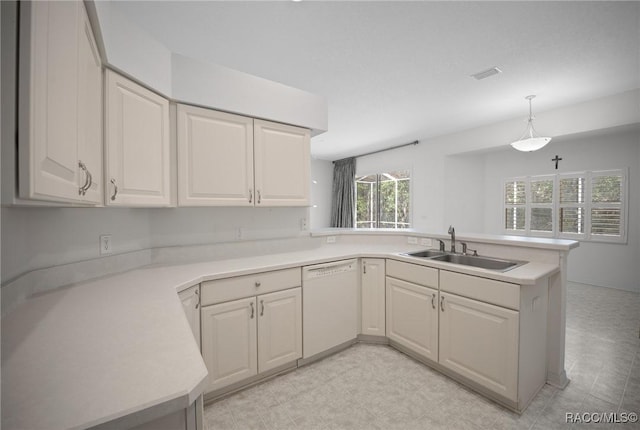kitchen featuring dishwasher, a sink, a peninsula, light countertops, and pendant lighting
