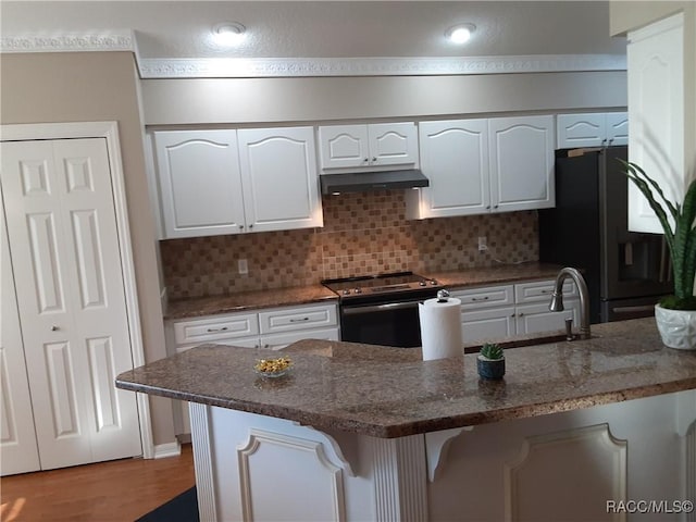 kitchen featuring backsplash, refrigerator, white cabinetry, and stainless steel range with electric cooktop