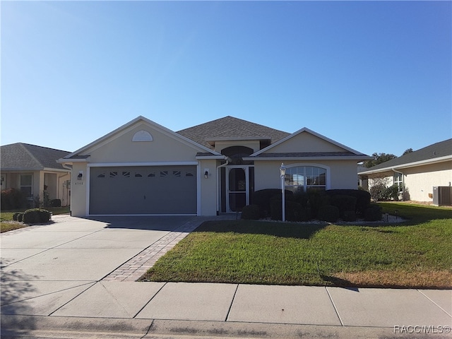 ranch-style home with central AC unit, a garage, and a front lawn