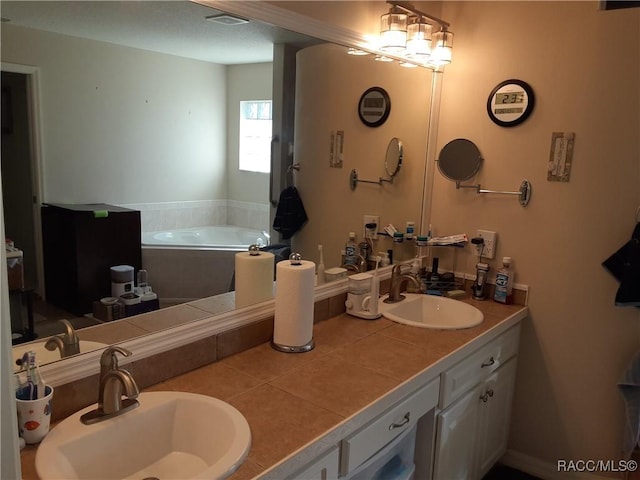 bathroom with tile patterned flooring, vanity, and a relaxing tiled tub